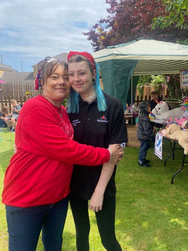 Two people hugging at an outdoor community event
