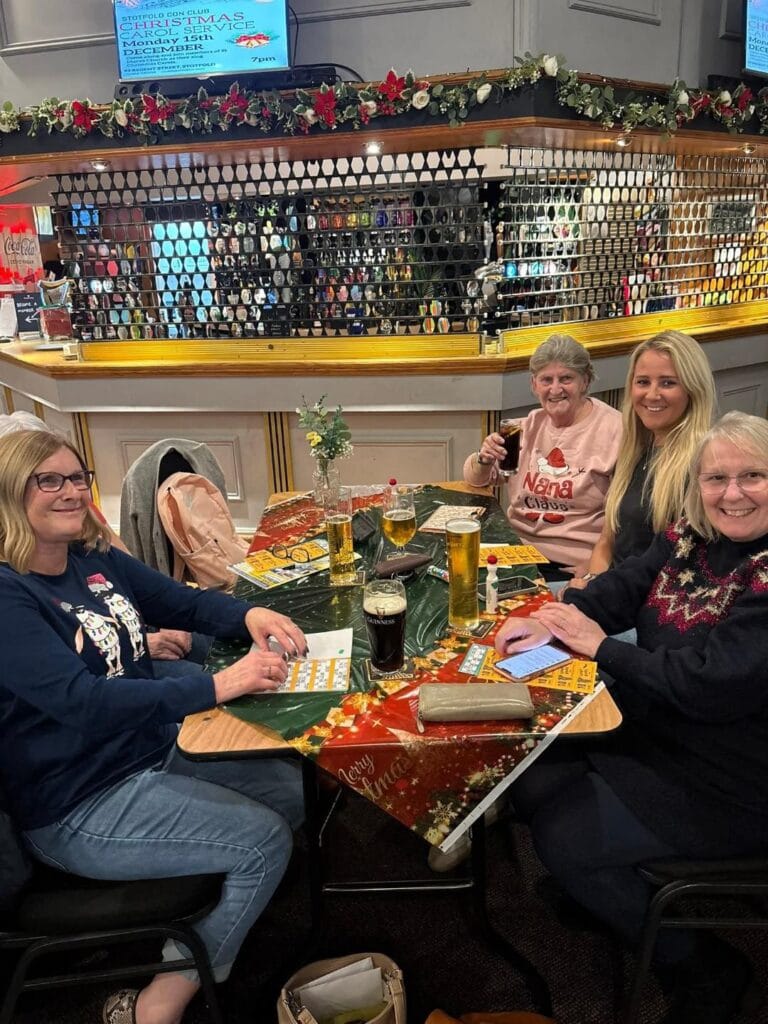 Friends enjoying Christmas drinks and bingo at a pub