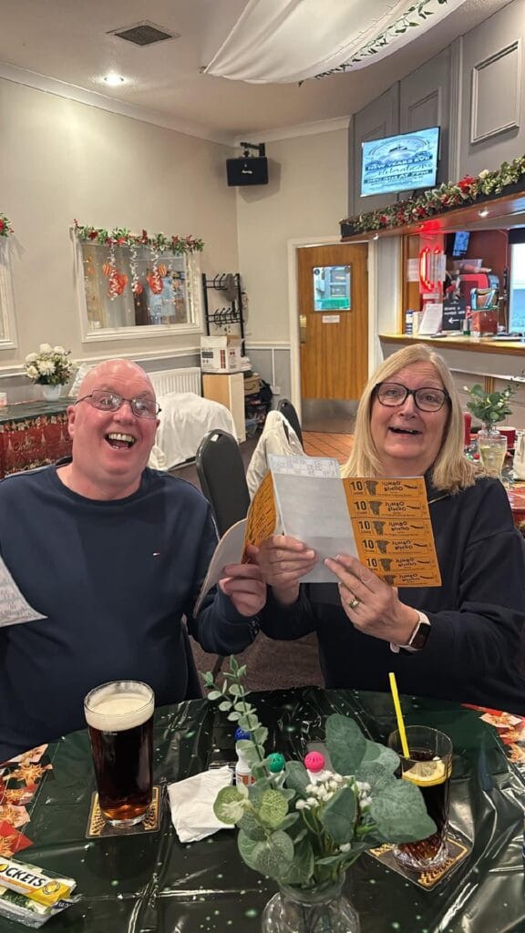 Smiling couple playing bingo in a festive pub.