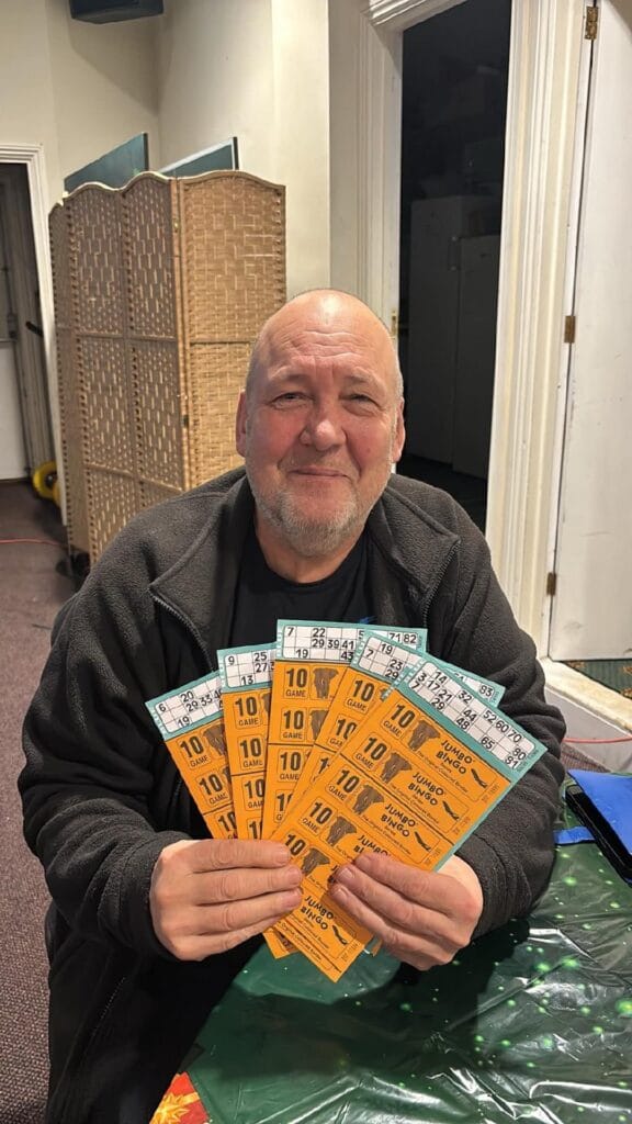 Man smiling while holding multiple bingo tickets