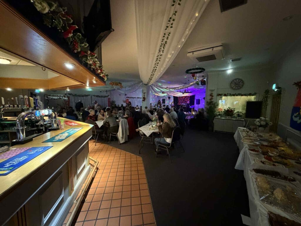 Decorated hall with guests dining and buffet tables