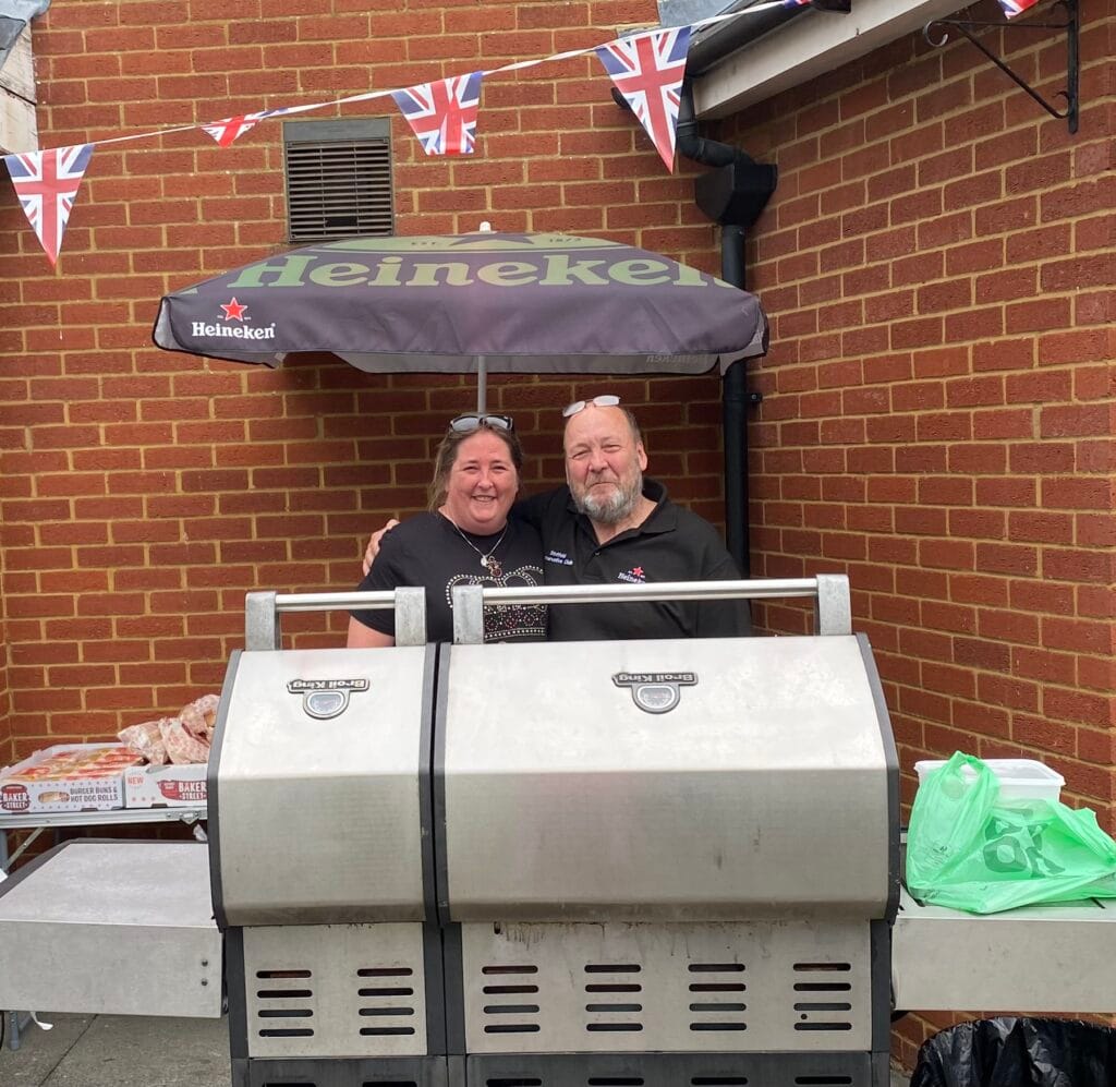 Smiling couple standing behind barbecue grill outdoors