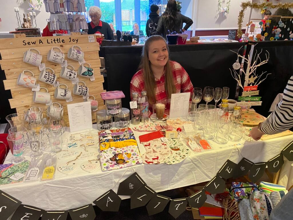 Woman selling handmade mugs and crafts at market
