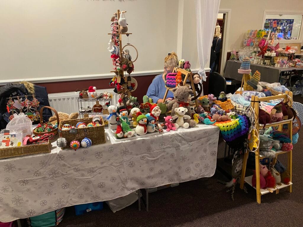 Craft fair stall displaying handmade knitted toys and gifts