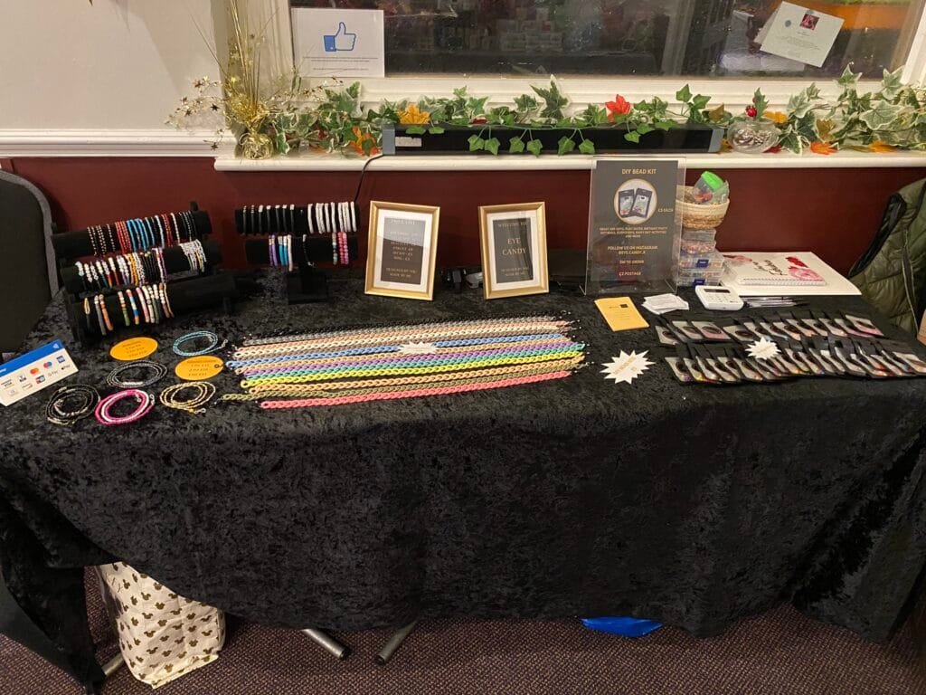 Colourful handmade bead jewellery displayed on black table.