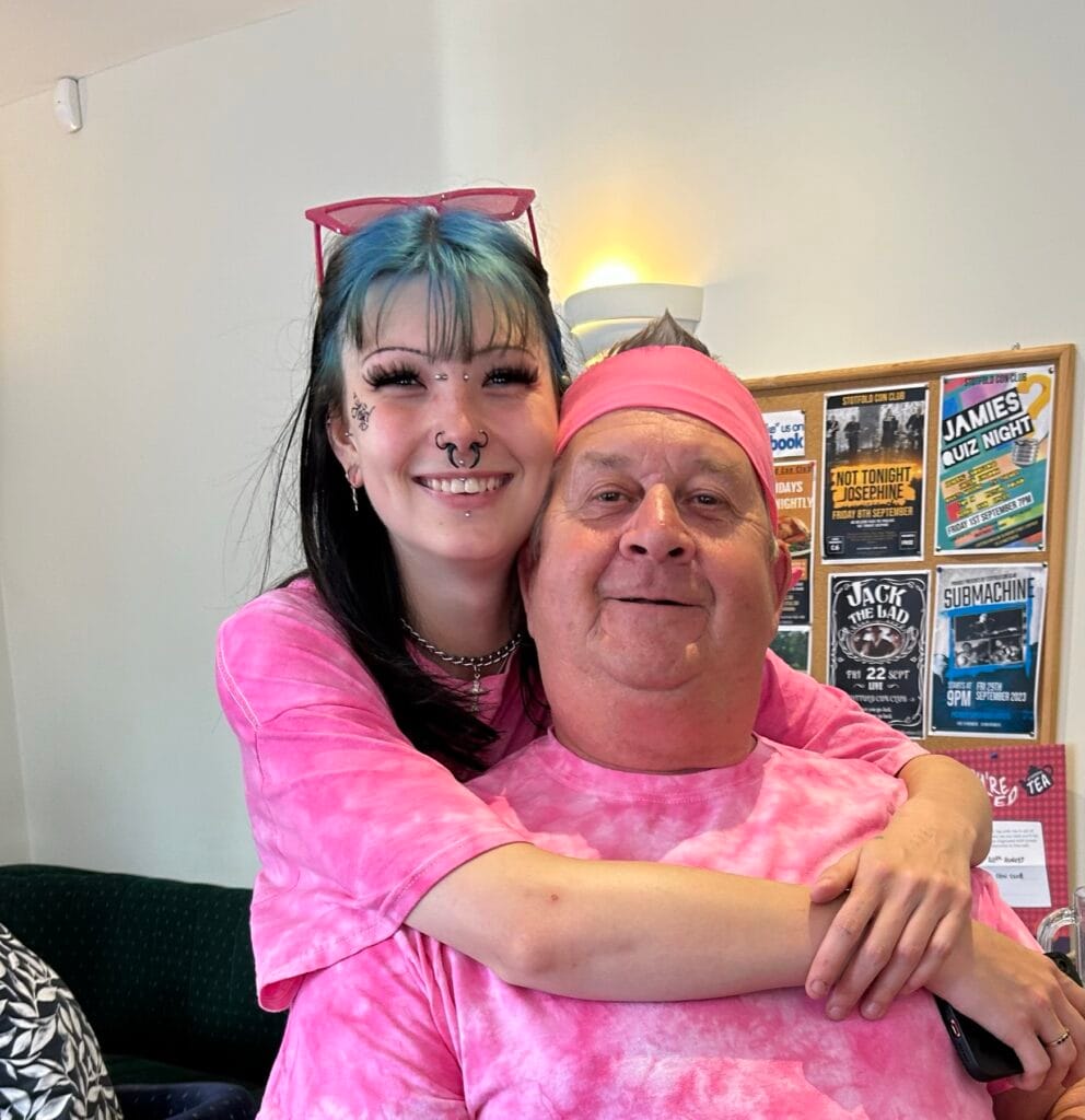Two people smiling in matching pink tie-dye shirts