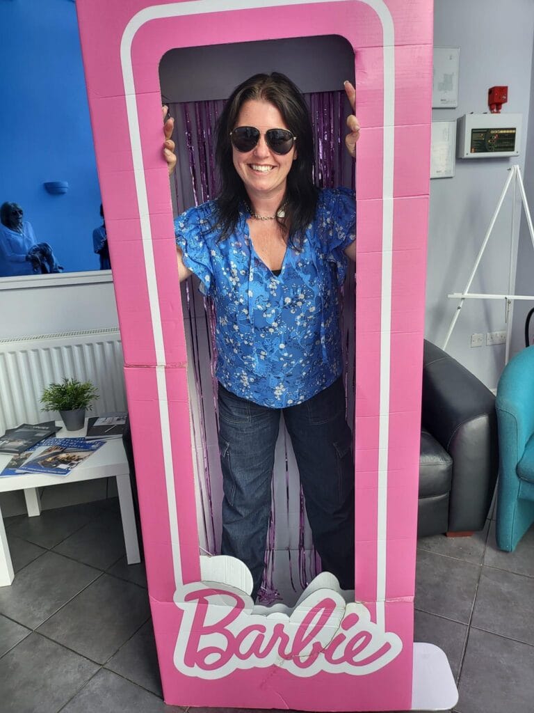 Smiling woman posing in a pink Barbie box