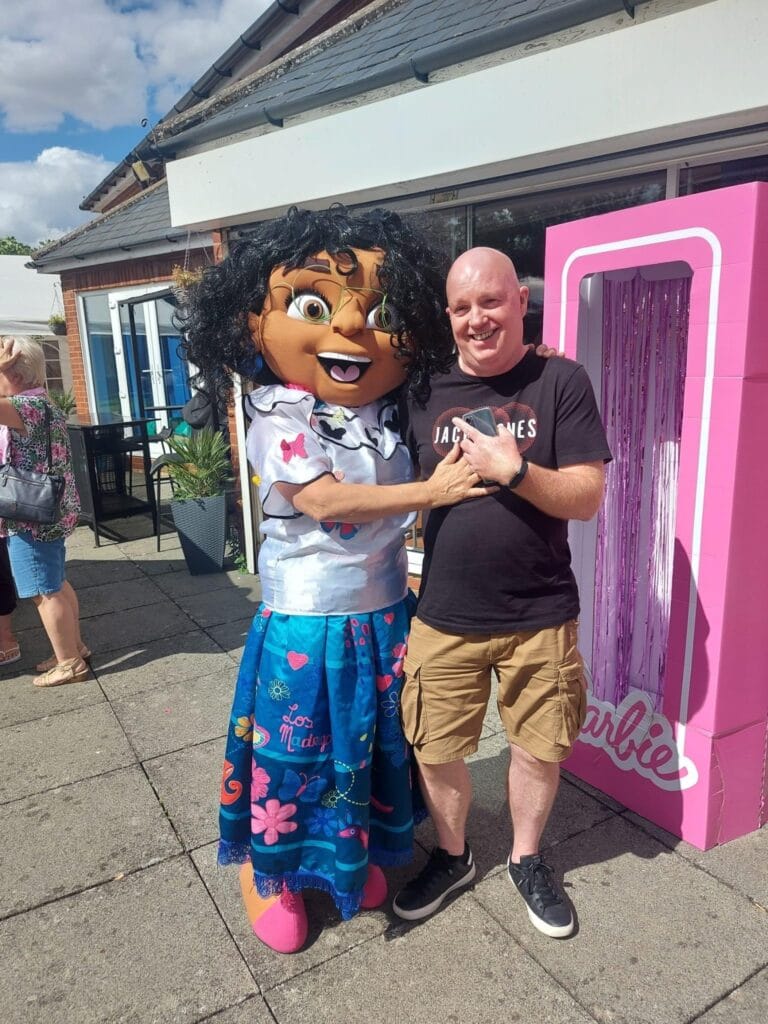 Man posing with cartoon character mascot outdoors