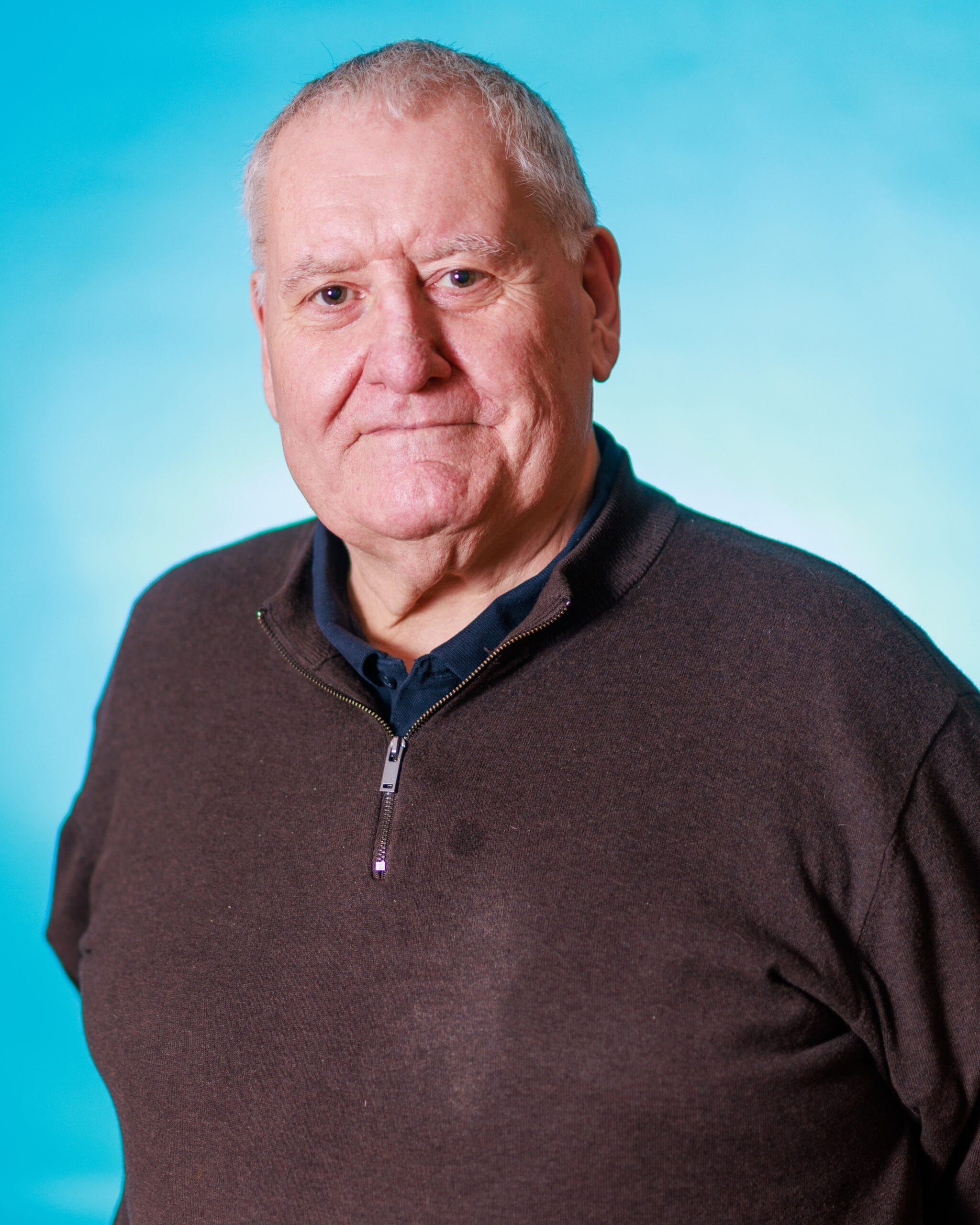 Older man smiling against blue background