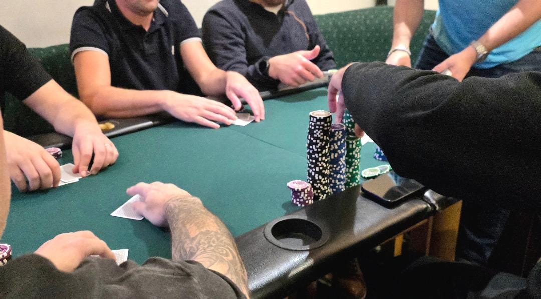 People playing poker around green table